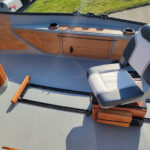 Padded adjustable oarsman seat on tracking rails with integrated side storage and cherry fly boxes.