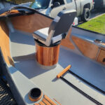 Cherry wood forward pedestal with built in ice box and etched storage door inside a drift boat.