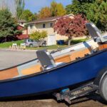 Dark blue 16 foot composite hybrid drift boat resting on a drift boat trailer in Missoula.