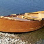 Handcrafted wooden drift boat build with Sawyer wood oars on the river water in Missoula, Montana.